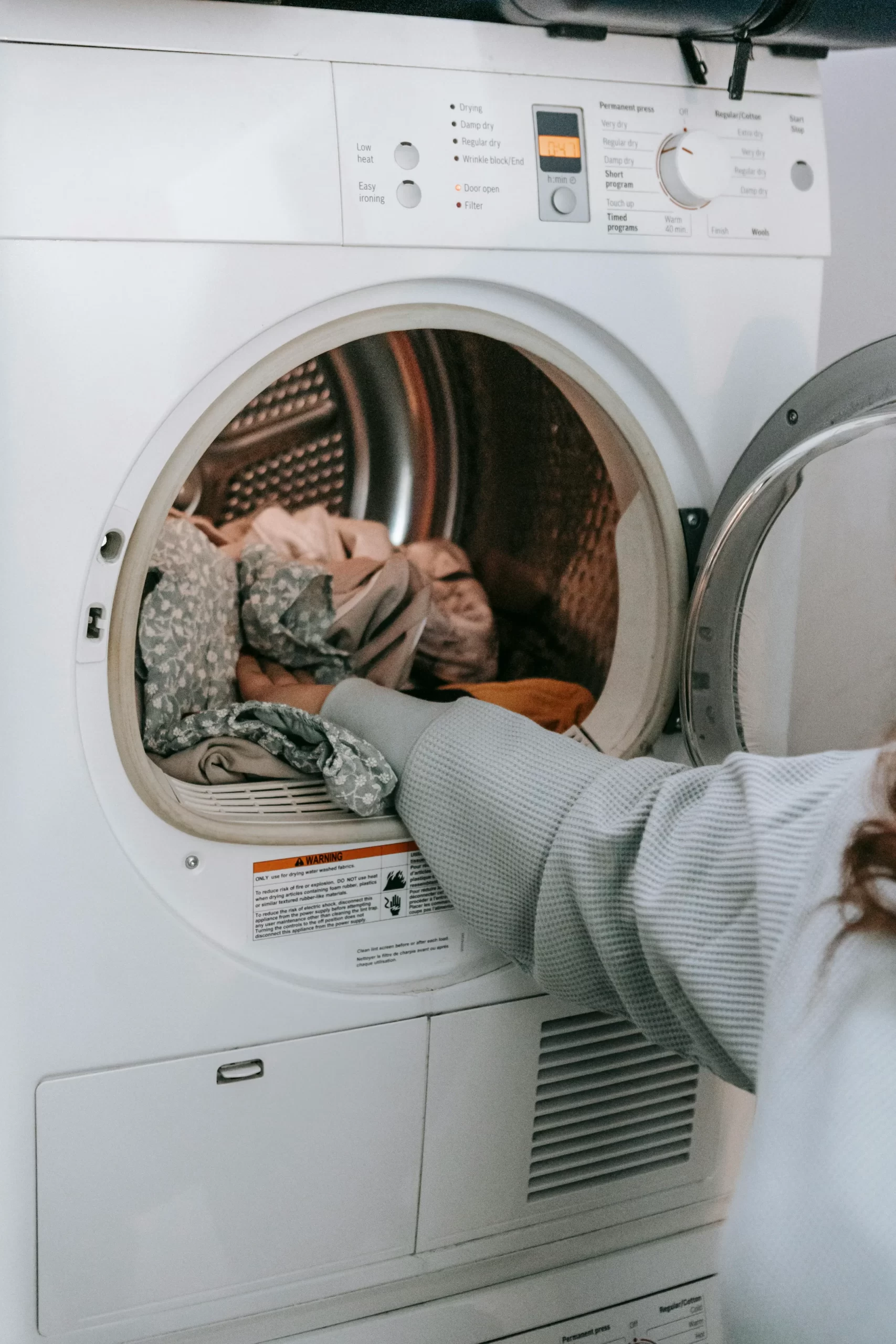 Cleaner loading laundry into washing machine for NDIS client